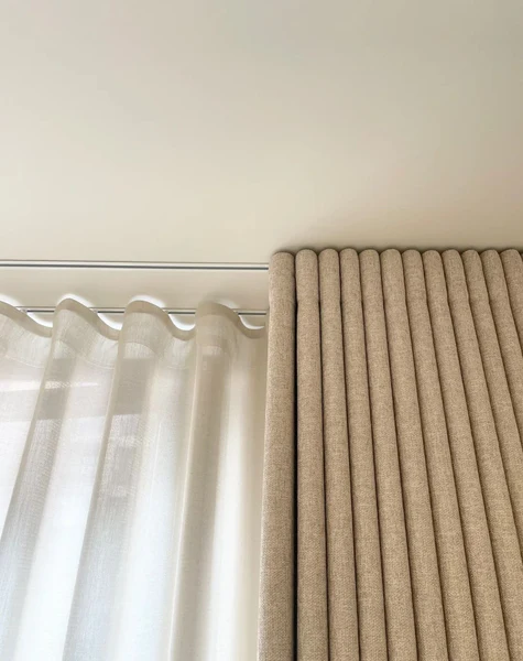close-up-of-ripple-folded-beige-linen-curtains-beside-white-sheers-on-ceiling-track